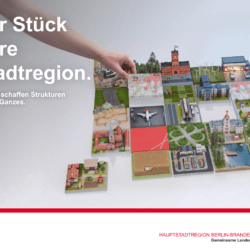 Unter der Überschrift "Stück für Stück für unsere Hauptstadtregion" werden verschiedene Puzzleteile zu einem Ganzen zusammengesetzt. Auf den Puzzleteilen sind unterschiedliche Nutzungen symbolhaft dargestellt (z.B. Landwirtschaft, Erneuerbare Energieträger, Verkehrsinfrastruktur, Wohngebäude). Am unteren Rand des Bildes sind Logos der Hauptstadtregion, des Landes Berlin, des Landes Brandenburg und für das 30-jährige Jubiläum der Gemeinsamen Landesplanung zu sehen.