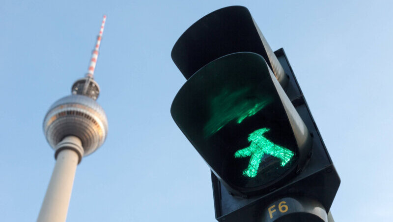 Blick auf Verkehrsampel mit grünem Ampelmännchen, im Hintergrund der Berliner Fernsehturm.