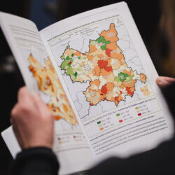 Das Bild zeigt eine Person, die eine aufgeklappte Broschüre hält. In der Broschüre ist eine Karte zur Bevölkerungsentwicklung zu sehen.