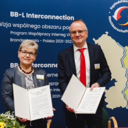 Dass Bild zeigt Brandenburgs Infrastrukturminister Detlef Tabbert und Anna Chinalska, Vorstandsmitglied der Wojewodschaft Lubuskie. Beide halten eine Absichtserklärung, in die Kamera zeigend, in der Hand.